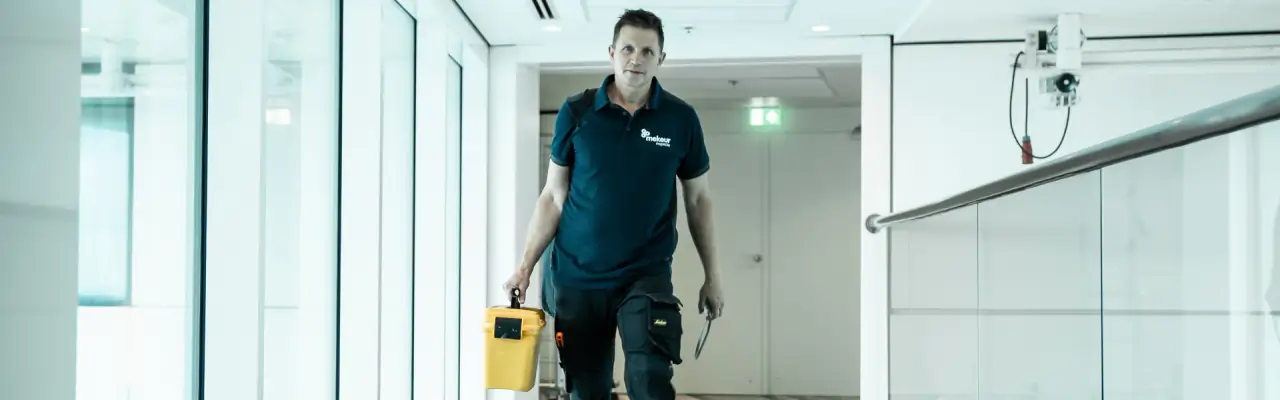 Inspecteur van Mekeur Inspectie loopt met zijn meetkoffer door een lichte gang