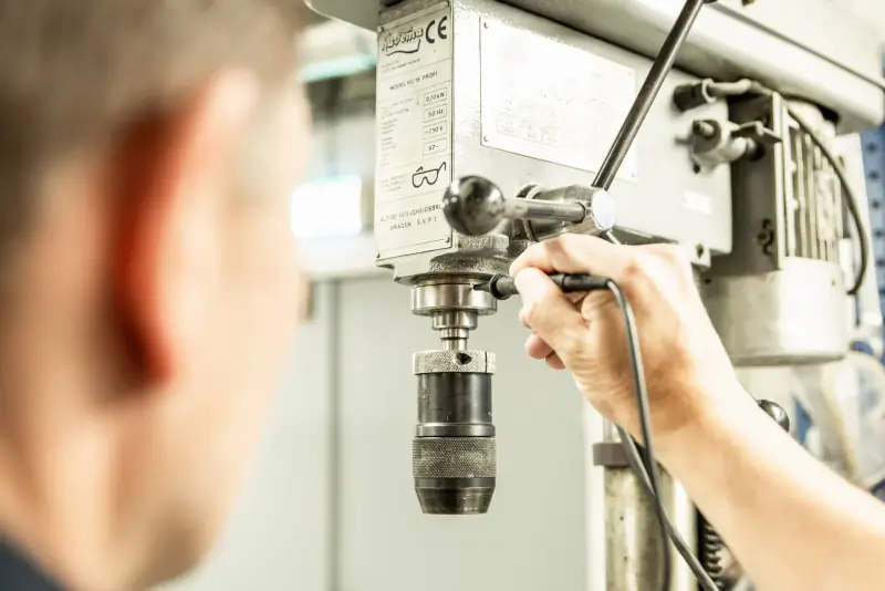 Inspecteur controleert een kolomboormachine in een werkplaats