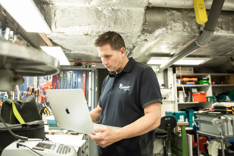 Inspecteur van Mekeur Inspectie werkt op een laptop in een industriële werkplaats