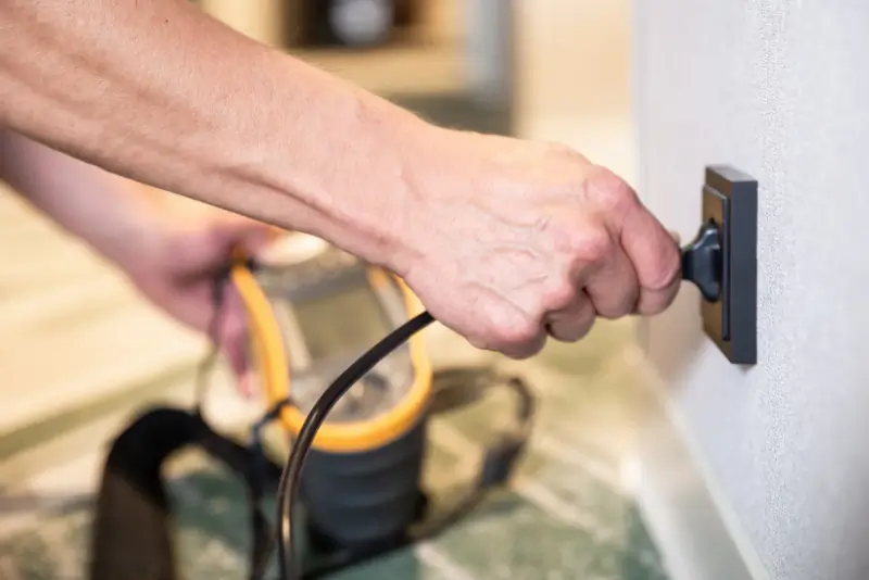 Inspecteur meet een wandcontactdoos door met een installatietester