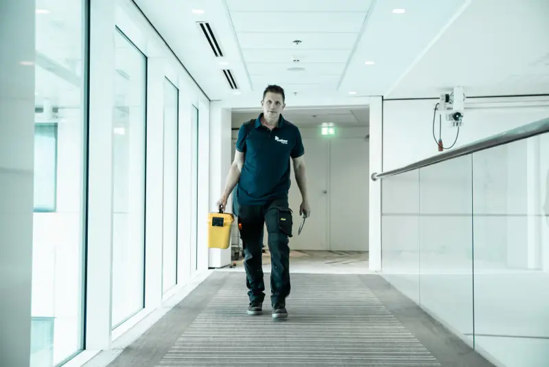 Inspecteur van Mekeur Inspectie loopt met zijn meetkoffer door een bedrijfspand